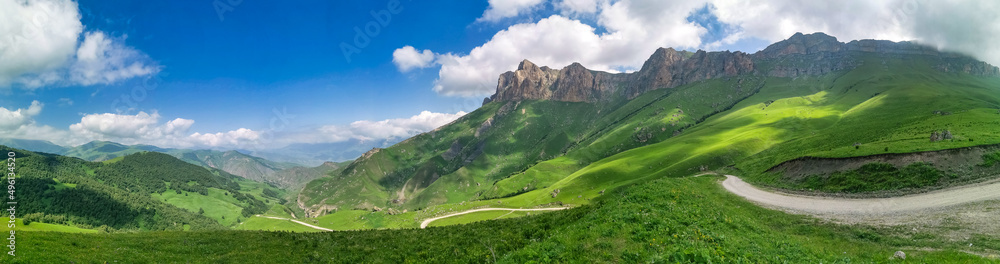 Naklejka premium The landscape of the green Aktoprak pass in the Caucasus, the road and the mountains under gray clouds. Russia.