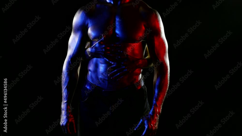 the middle plan of a muscular male torso with golden metallic skin. the woman stands behind the man and slides hands over his stomach and chest. red, blue and white light. without faces. dark key
