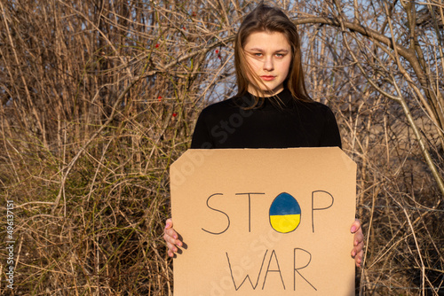 Angry Ukrainian girl  protesting war conflict raises banner with inscription massage text on map "Stop WAR". Peace, no war, stop aggression.  Stop the war in Ukraine. The concept of peace in Ukraine