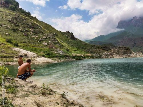 A man and a child are fishing on the mountain lake Gizhgit in Kabardino-Balkaria. Elbrus Region of Russia June 2021.