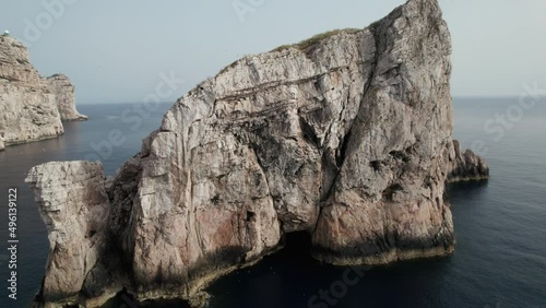 Aerial top view of waves break on rocks in a blue ocean at sunset. Sea waves on beautiful beach aerial view drone 4k shot. Bird's eye view of an empty stone rock cliff from above in Sardinia