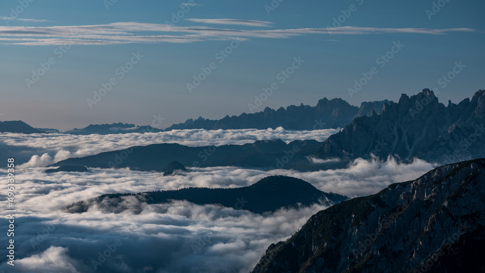 Low inversion clouds between mountain layers during blue sky day in the Dolomite Alps in South Tyrol, Italy.