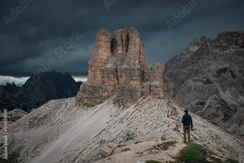 Man taking photos with camera with view to Sasso di Sesto mountains peak in the Dolomite Alps in South Tyrol with dramatic dark sky, Three Peaks Nature Reserve, Italy. photo