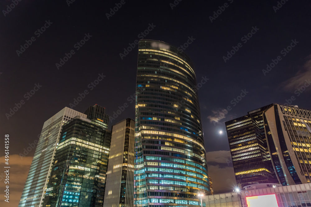 Obraz premium The Moon at Night Making Her Way Between Towers of La Defense Business District