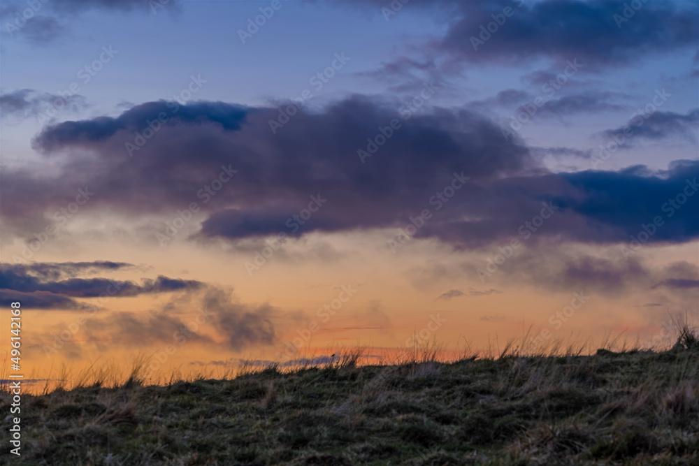 Blue Hour in the Sky Behind Top of the Hill Moving Clouds Over Landscape