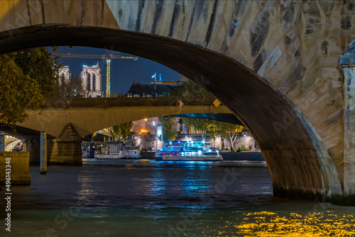 Blue Boat Cruise on Seine River at Night With Stone Bridges and Notre Dame Cathedral in Paris