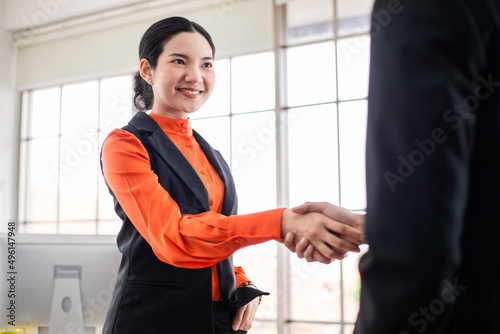 Smiling Asian woman hand shaking with colleague partnership for successful agreement. corporate business people dealing with customer in the office