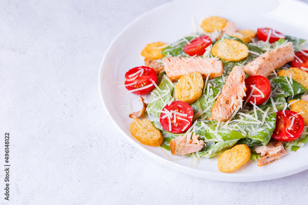 Caesar salad with red fish (salmon, trout), cherry tomatoes, croutons, parmesan cheese and romaine. Traditional American dish. Copy space. Close-up, selective focus. Caesar salad with red fish (salmon, trout), cherry tomatoes, croutons, parmesan cheese and romaine. Traditional American dish. Copy space. Close-up, selective focus.
