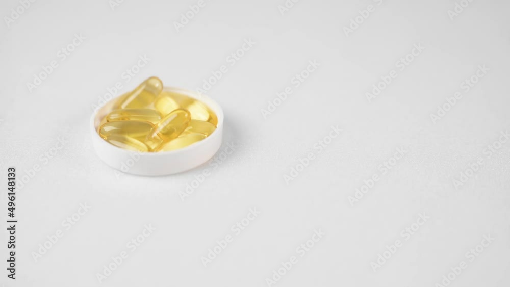 A woman's hand takes a capsule of organic vitamins from the table. Taking vitamin E, fish oil, Omega 3, vitamin D. Taking dietary supplements A woman's hand takes a capsule of organic vitamins from the table. Taking vitamin E, fish oil, Omega 3, vitamin D. Taking dietary supplements
