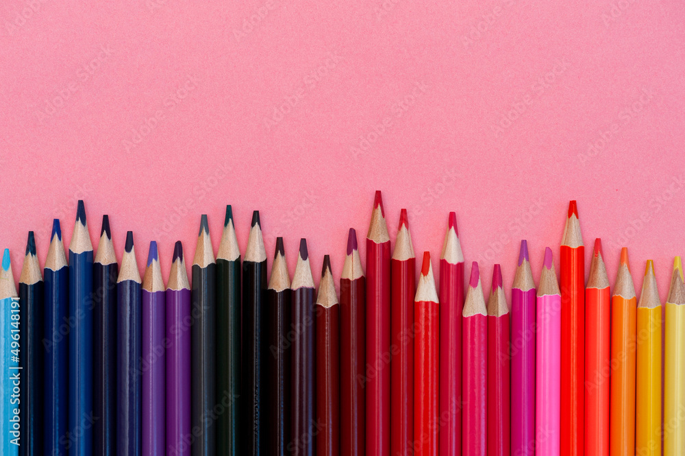 Colored pencils on a pink background, copy space