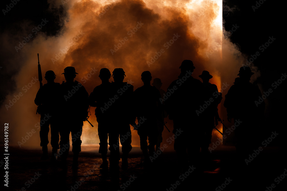 silhouette group of thai soldiers special forces full team in uniform walking action through smoke and holding gun on hand and over the lighting background.