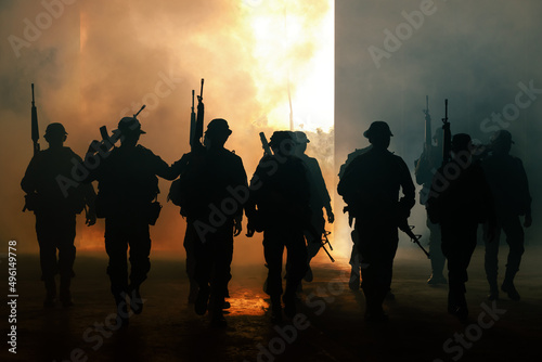 silhouette group of thai soldiers special forces full team in uniform walking action through smoke and holding gun on hand and over the lighting background.