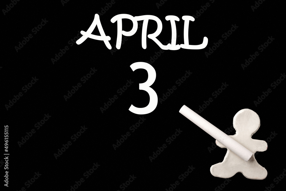 A small white plasticine man writing the date 3 April on a black board. Business concept. Education concept.