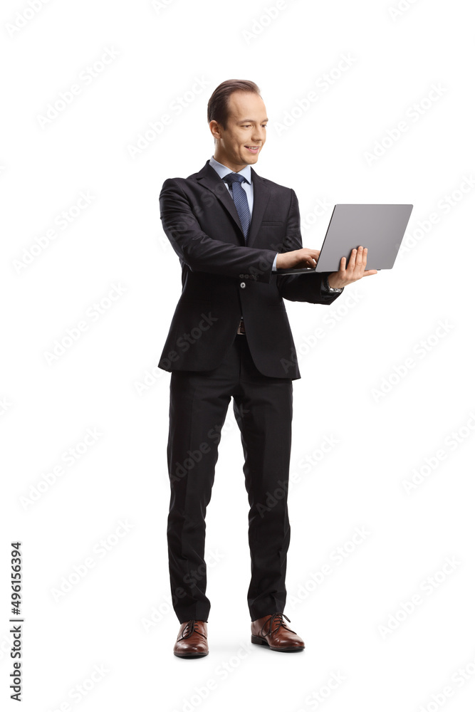 Full length portrait of a businessman working on a laptop computer and standing Full length portrait of a businessman working on a laptop computer and standing