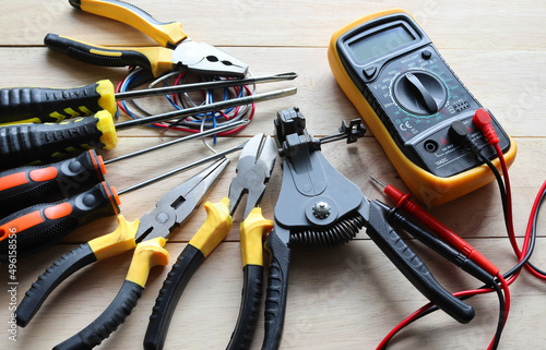 Different electrical tools for repair and maintenance on wooden background closeup.