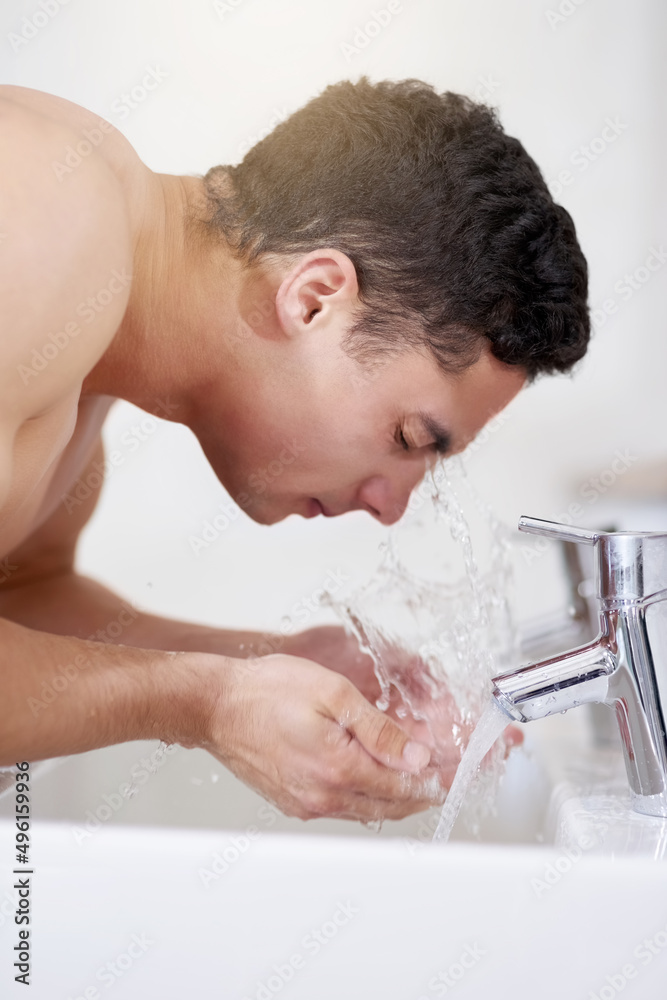 He knows how to keep it clean. Shot of a handsome young man washing his face at the bathroom sink. He knows how to keep it clean. Shot of a handsome young man washing his face at the bathroom sink.