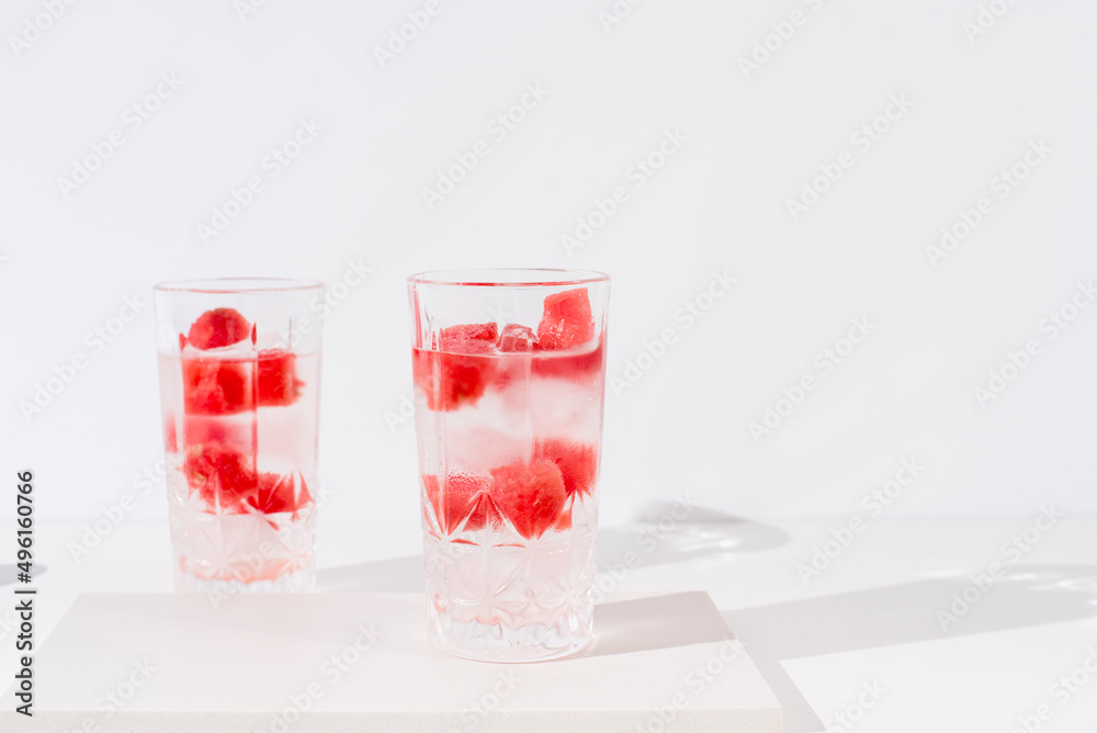 Dos vasos de zumo de sandía con trozos de sandia y hielo sobre fondo claro Dos vasos de zumo de sandía con trozos de sandia y hielo sobre fondo claro