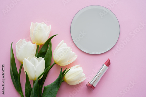 top view of white tulips near mirror and lipstick on pink. © LIGHTFIELD STUDIOS