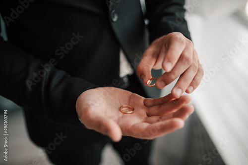 The groom holds the gold wedding rings with his fingers. selective focus