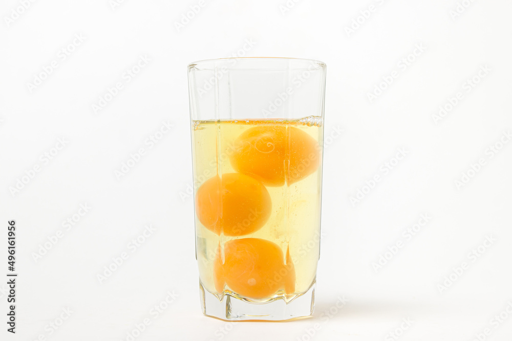 Broken raw chicken eggs in a glass on a white background. Chicken egg yolk. Drinking raw chicken eggs Broken raw chicken eggs in a glass on a white background. Chicken egg yolk. Drinking raw chicken eggs