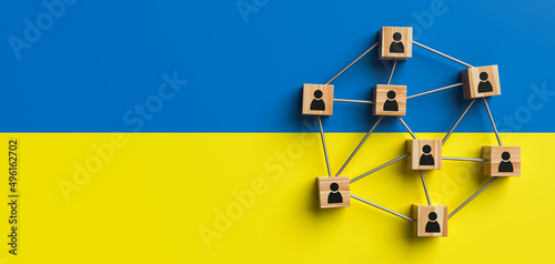 Wooden blocks with people icon on the background of Ukraine flag. Concept of unity and solidarity of people. Copy space. 3d rendering.