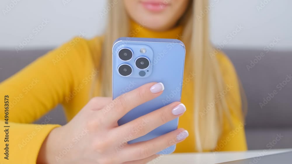Young girl browsing mobile phone app. Blonde woman using modern blue smartphone for communication online Young girl browsing mobile phone app. Blonde woman using modern blue smartphone for communication online