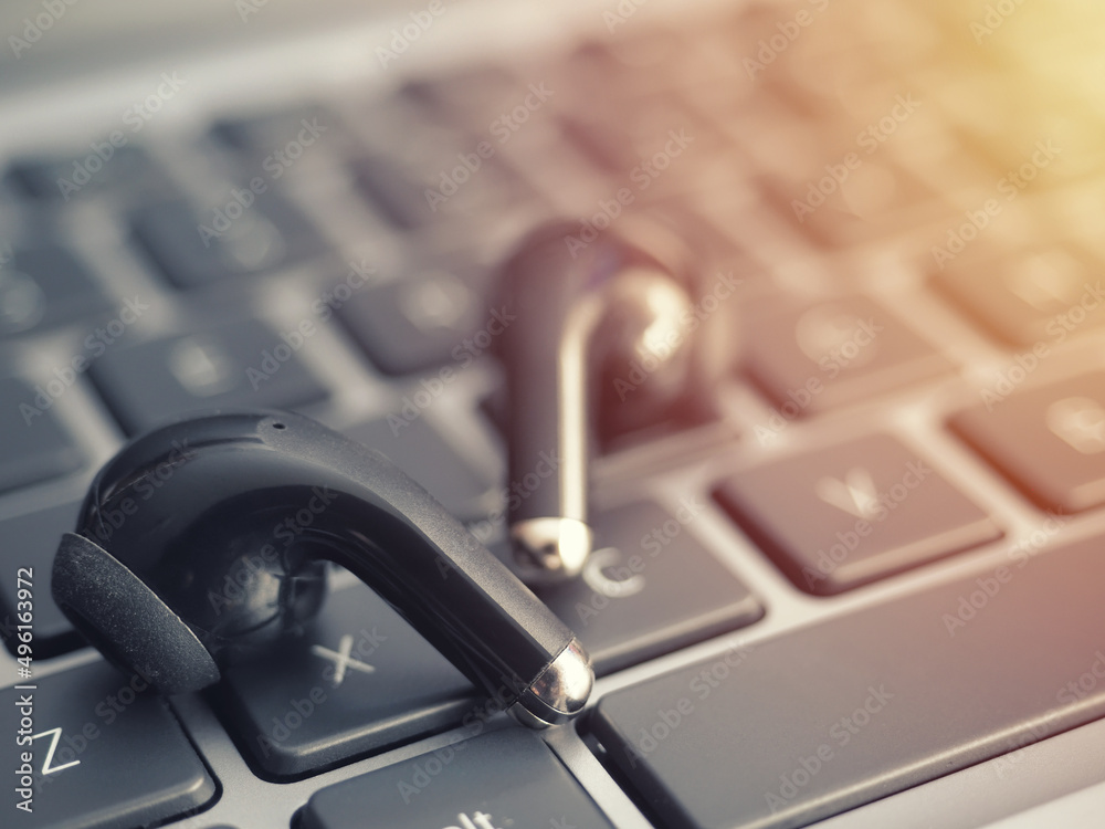 Wireless headphones on a laptop keyboard. Watching movies and listening