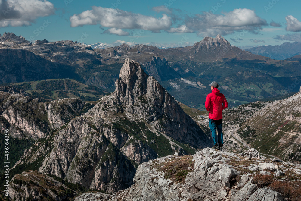 Man on summit of Croda Negra looking to mountain summit of Hexenstein at Passo di Falzarego during sunny blue sky day in the Dolomite Alps, South Tyrol Italy.