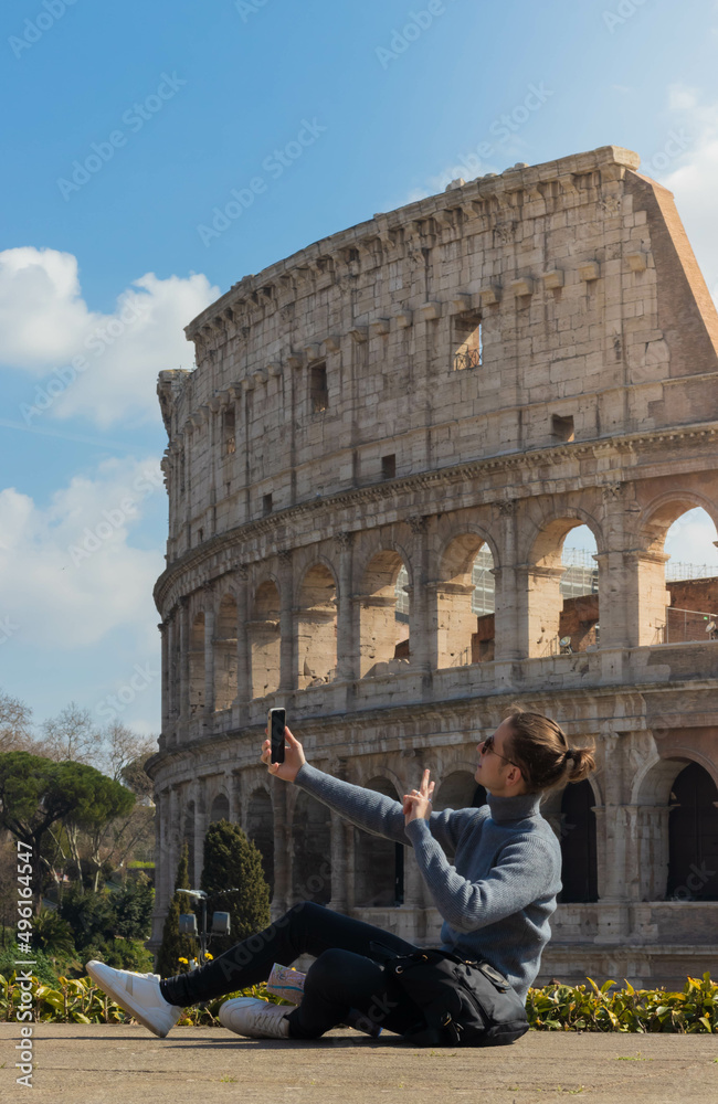 Young man taking a selfie photo and waving with the Colosseum of Rome