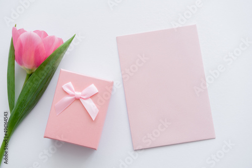 top view of envelope near gift box and pink tulip on white. © LIGHTFIELD STUDIOS