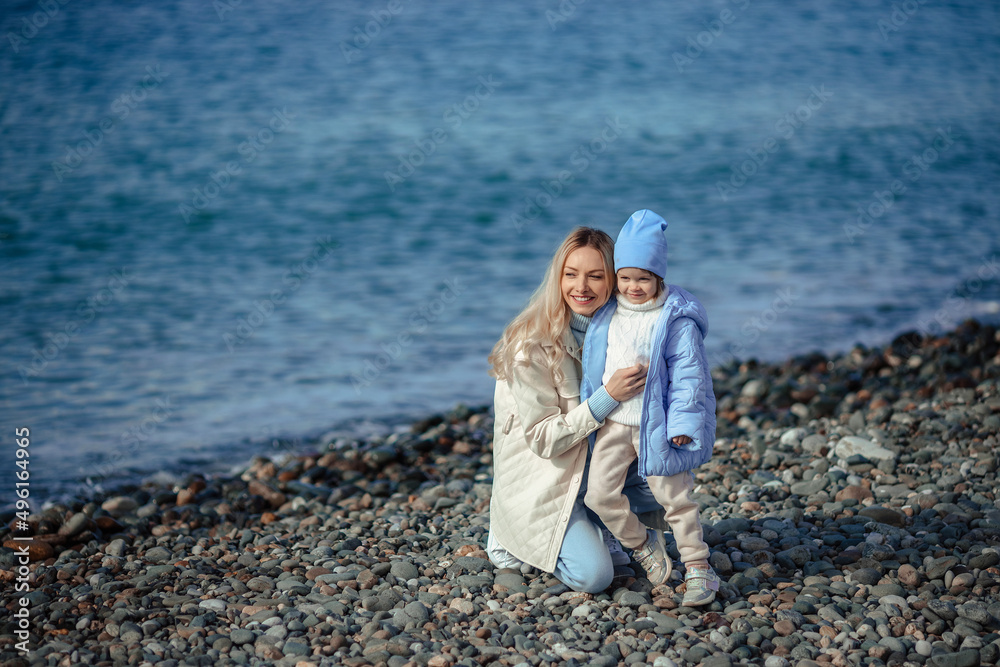 family vacation at sea in autumn or spring. Happy family mother and daughter on a walk along the seashore