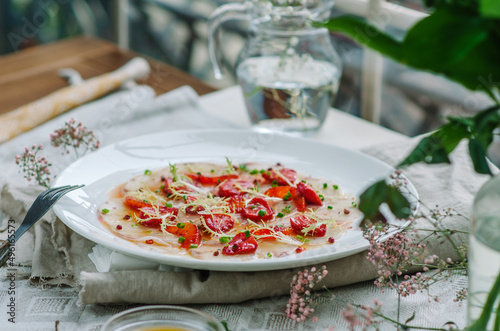 sea bass carpaccio with baked strawberries and citrus dressing. Dish in the restaurant, strawberry menu. Summer light dish for gourmets.