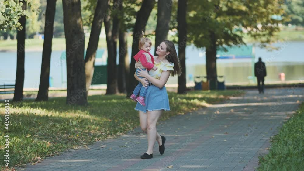 A young mother walks with her daughter in the park. A young mother walks with her daughter in the park.