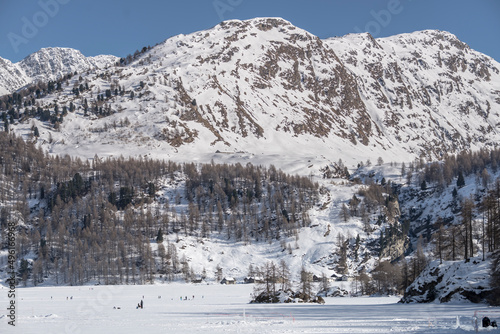 people on frozen mountain lakes and snowy rocky slopes, near Plaun da Lej, Switzerland photo