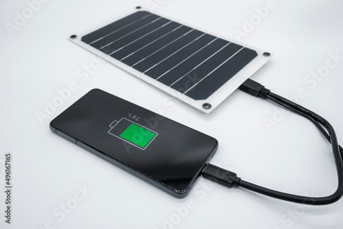 View of smartphone charging using portable solar photovoltaic panel,renewable green energy tech