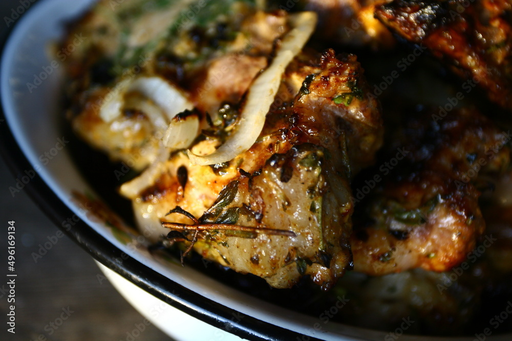  grilled or roasted pieces of fat well done pork meat with herbs in rustic style on white iron dish