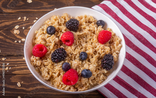 Oatmeal with berries in a bowl on wooden background