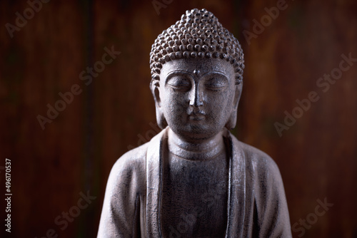 Meditating Buddha Statue on dark wooden background. Close up. Copy space.