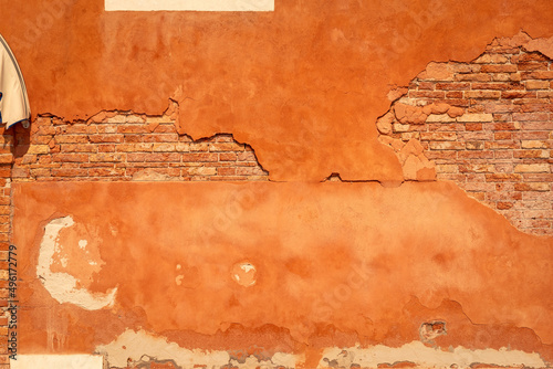 Brick orange wall with old paint cover falling off texture, Murano Venice Italy