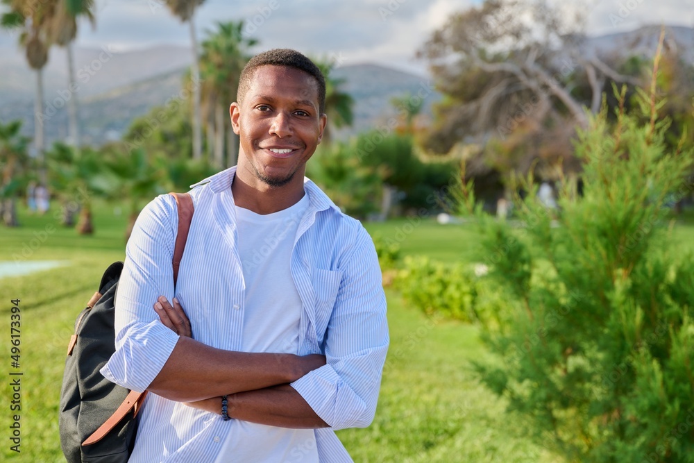 Outdoor portrait of African American man with crossed arms looking at camera, copy space
