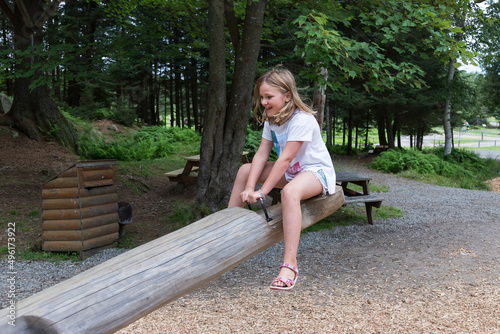 Wallpaper Mural Cute smiling little girl in summer clothes sitting on wooden seesaw in playground Torontodigital.ca