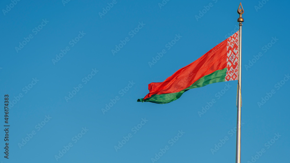 State flags of the Republic of Belarus are waving in the wind on blue sky background. Space for text. State flags of the Republic of Belarus are waving in the wind on blue sky background. Space for text.