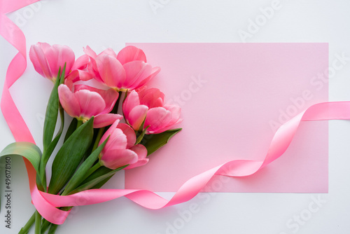Fototapeta Naklejka Na Ścianę i Meble -  top view of bouquet with tulips near ribbon and pink paper on white.