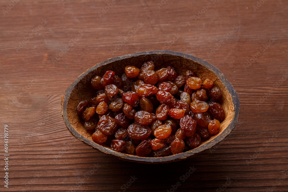 Raisins in a bowl of coconut shell on a wooden table. Raisins in a bowl of coconut shell on a wooden table.