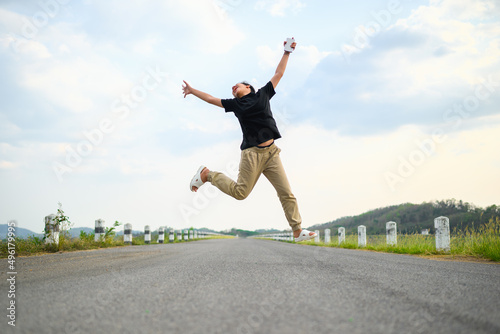 Cheerful child is jumping with joy on the country road, happy girl feel fun and free to stay outdoor in the countryside