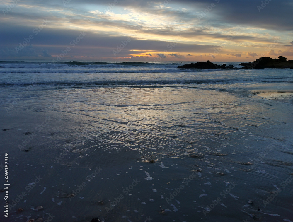 Aerial view of the sea, beach boulders and waves at sunset. Waves crashing on sandy beach. Aerial view of the sea, beach boulders and waves at sunset. Waves crashing on sandy beach.