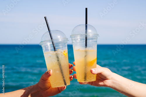 Cold lemonade in female hands by the sea in summer