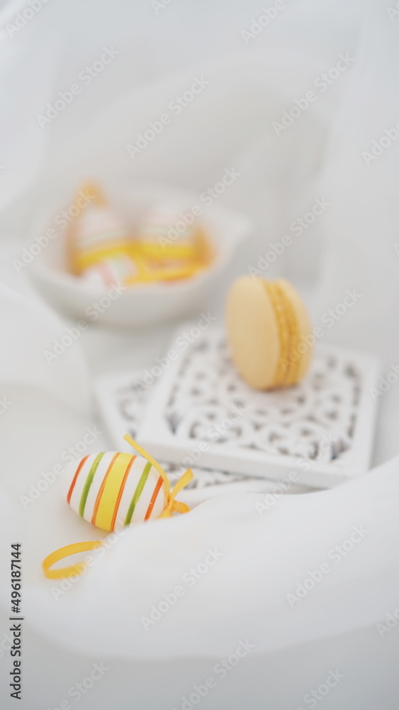 Easter setup - Easter eggs and yellow french macarons decorations on white background
Easter setup - Easter eggs and yellow french macarons decorations on white background