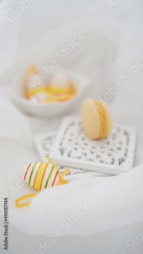Easter setup - Easter eggs and yellow french macarons decorations on white background 