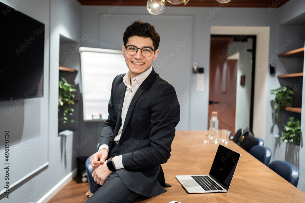 A manager with glasses in a suit uses a laptop computer works in an office coworking space A manager with glasses in a suit uses a laptop computer works in an office coworking space